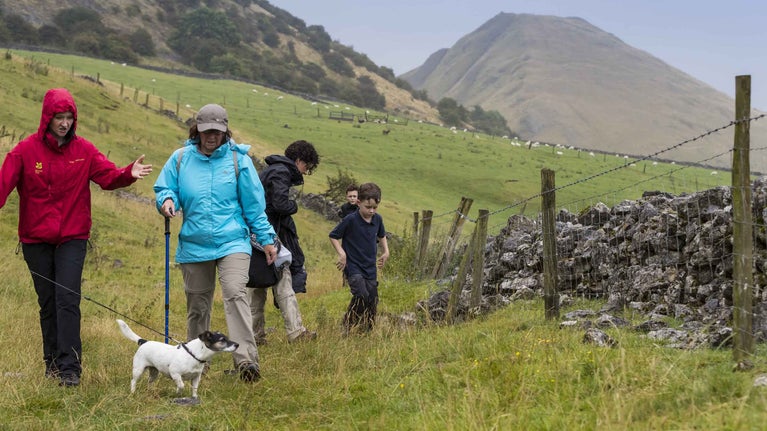 Visitors on a guided walk with Thorpe Cloud in the distance at Ilam Park, Dovedale and the White Peak, Derbyshire.